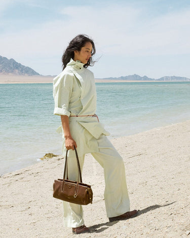 Yore Baguette Bag in Sandal color, made of vegetable-tanned leather, on a beach.