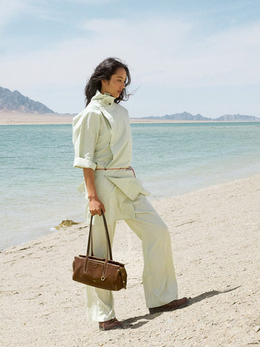 Yore Baguette Bag in Sandal color, made of vegetable-tanned leather, on a beach.