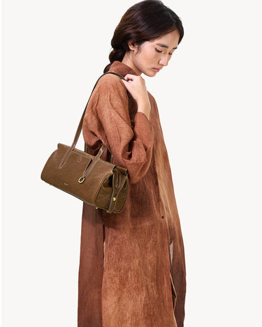 Yore Baguette Bag in Sandal color, a structured olive-brown leather shoulder bag carried by a woman in a brown dress.