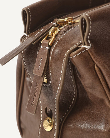 Brown Yore Baguette Bag: vegetable-tanned leather, gold hardware, white stitching. Embossed Songmont logo.