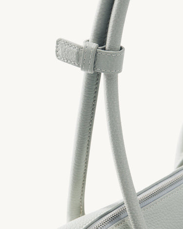 Close-up of light grey full-grain leather Yore Toast Bag with stitched strap detail and silver zipper.