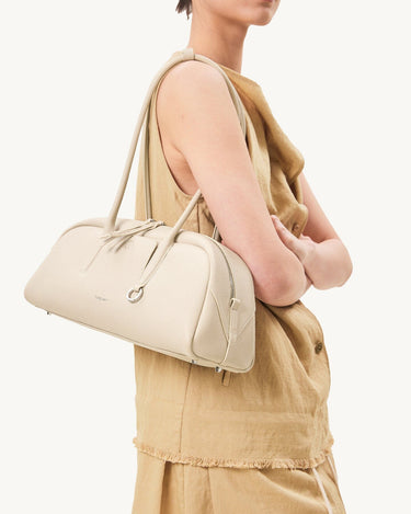Yore Toast Bag in Cloud, a cream pebble-grain leather handbag with rounded shape and silver hardware.