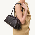 Yore Toast Bag in Ebony, a dark brown leather handbag with white stitching, worn by a model.