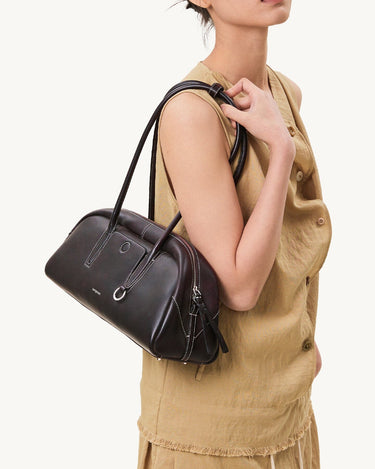 Yore Toast Bag in Ebony, a dark brown leather handbag with white stitching, worn by a model.